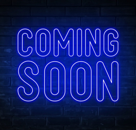 Coming soon - blue neon light word on brick wall background